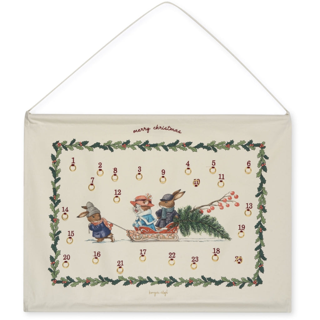 A Christmas Calendar (Final Sale) made of organic cotton, hanging on a wall, featuring a whimsical design with rabbits in winter clothing, surrounded by a festive border of greenery and red berries, with embroidered.