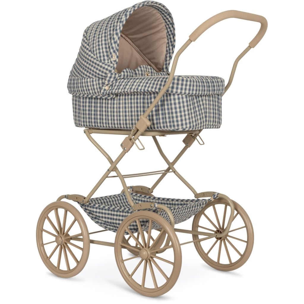 A vintage-style Doll Pram - Blue Checkered with a classic checkered pattern in tan and navy. It features a large canopy, a soft interior, and an elegant golden frame with large spoked wheels.