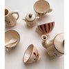 A Konges Sløjd Pretend Play Porcelain Tea Set with a soft beige and maroon design, featuring a teapot, lid, four cups, and a milk jug, arranged on a light surface.