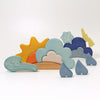 A set of Grimm's Weather Building Block Set is arranged on a white surface. The play pieces include a sun, clouds, raindrops, a lightning bolt, a snowflake, and a wind symbol, each painted in soft pastel hues. Perfect for young builders to create their own weather stories!