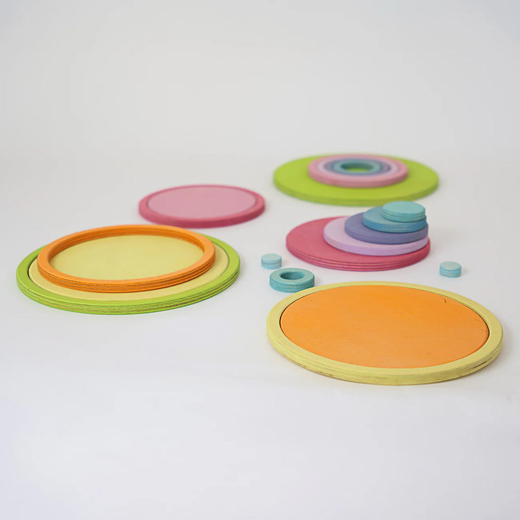 Grimm's Concentric Circles and Rings Building Set - Pastel features vibrant orange, yellow, green, pink, purple, and blue wooden discs arranged on a white surface—ideal for creative building and balance games.