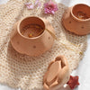 The Christmas Tree Storage Box sits on a crocheted mat beside wooden bowls with jewelry, a carved turtle, and pink flowers. Soft sunlight enhances the charm, creating a warm and inviting atmosphere.