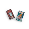 A small toy robot with red headphones sits beside an open box and a closed box featuring a bear holding a lantern, labeled "Moulin Roty Storybook Lantern - The Minouchkas" and "Ma Lampe à Histoires," hinting at magical storytelling.