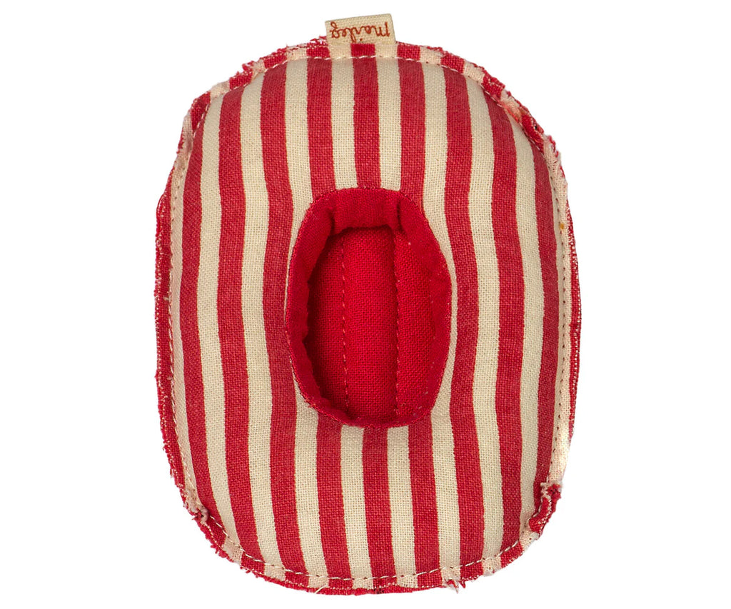 A Maileg Beach Raft, Small Mouse - Red stripe in the shape of an oval with a circular hole in the middle, revealing the red interior cotton fabric. A small brown label with text is attached to the top edge. The fabric appears slightly frayed at the edges, reminiscent of something for baby mice sizes.