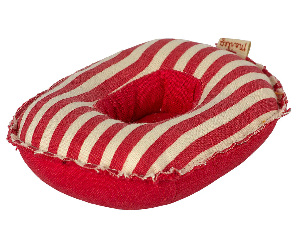 A small, rectangular-shaped Maileg Beach Raft, Small Mouse - Red stripe with a red and white striped cotton fabric design and a hole in the center, resembling a donut. The Maileg Beach Raft has a worn, frayed appearance, similar to small boat cushions, and a small brown tag is attached to one edge.