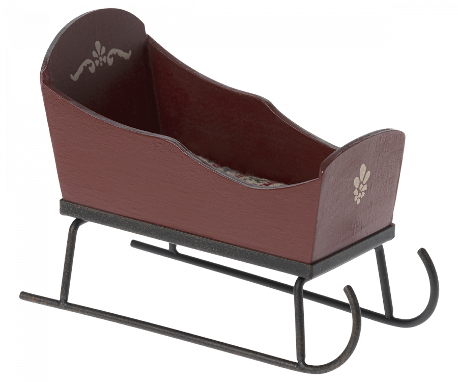 A small, decorative Maileg Christmas Sleigh - Red with a red body and ornate hand-painted details on the sides. The sleigh has black metal runners and curved front rails, ensuring it’s both stylish and functional.