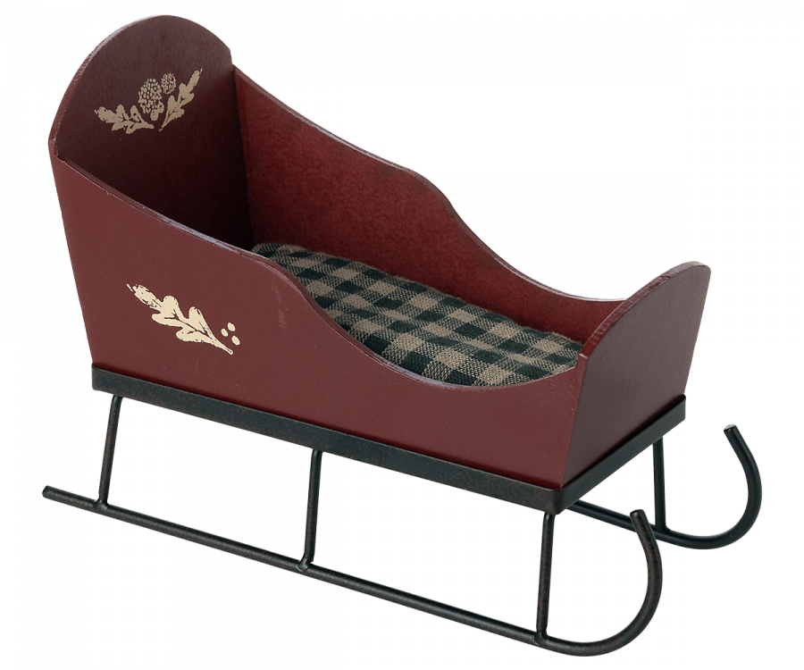 The Maileg Christmas Sleigh - Red is a charming small decorative piece, featuring a rich burgundy body beautifully adorned with hand-painted gold floral designs. Inside, it boasts a green and beige plaid cushion, and it rests elegantly on black metal runners. This sleigh's vintage and festive appearance makes it the perfect addition to your holiday decor.