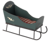 The PRE-ORDER: Maileg Sleigh, Mini - Green features handpainted details, black metal runners, and a red and white checkered cushion. This empty decorative sleigh is shown against a plain light background. Estimated arrival: Early September.