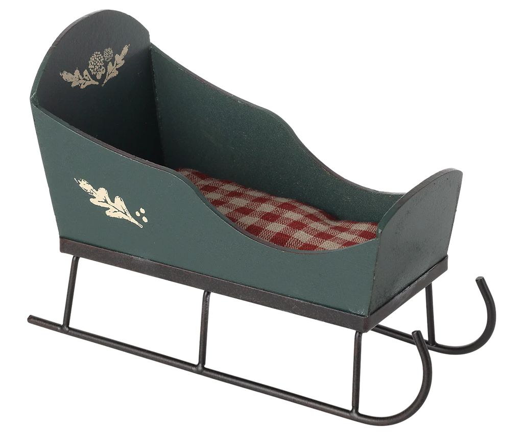 The PRE-ORDER: Maileg Sleigh, Mini - Green features handpainted details, black metal runners, and a red and white checkered cushion. This empty decorative sleigh is shown against a plain light background. Estimated arrival: Early September.