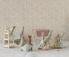 Six small fabric bunny dolls are in a nursery featuring the Maileg Nursery Table, Micro - Red Checker, surrounded by baby furniture, patterned wallpaper, and cozy blankets for a playful, charming scene.