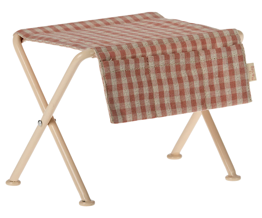 The Maileg Nursery Table, Micro - Red Checker is shown with a small folding stool featuring beige metal legs and a red and white checkered seat, perfect for nurseries. Set against a white background.