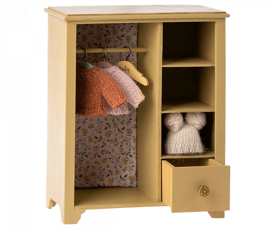 A Maileg Wardrobe, Large - Yellow with an open door revealing a floral patterned interior, hanging knitted clothes, and a drawer slightly open with items inside.