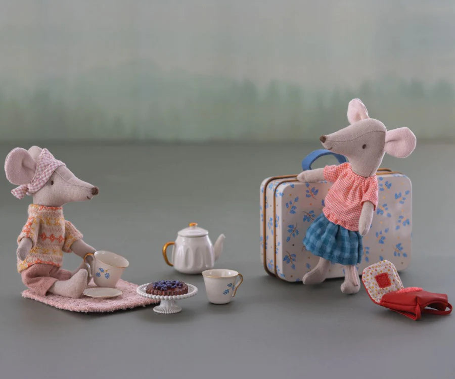 Two stuffed toy mice having a tea party, with one seated at a small table and the other standing beside a Maileg Miniature Afternoon Treat Tea Set - Blue Madelaine, surrounded by teacups and a teapot on a gray background.
