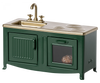 A Maileg Kitchen - Dark Green unit with a sink, faucet, and stove top, featuring gold accents and an oven door slightly ajar showing a loaf of bread inside.