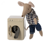 A stuffed mouse toy from a mouse family in a plaid shirt and jeans leaning on a Maileg Washing Machine For Mice, with one hand inside the drum, against a plain background.