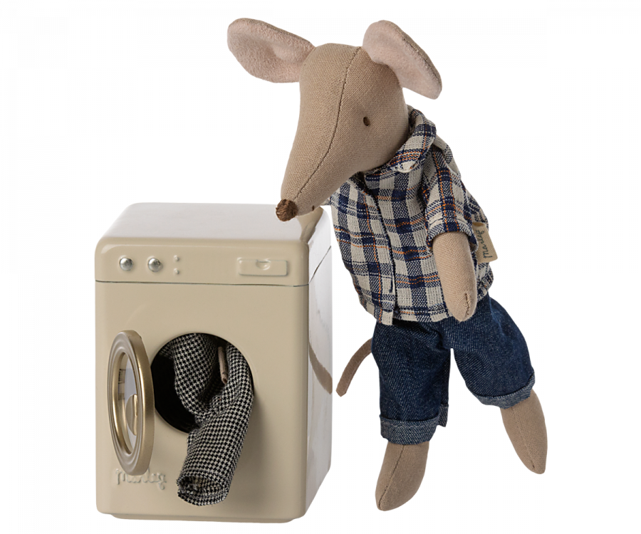 A stuffed mouse toy from a mouse family in a plaid shirt and jeans leaning on a Maileg Washing Machine For Mice, with one hand inside the drum, against a plain background.