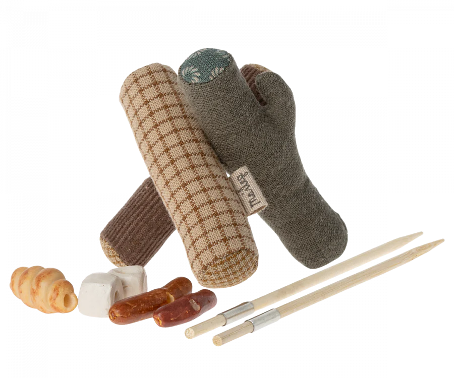 An assortment of dog toys and treats, including a Maileg Happy Camper Set - Gift Wrapped, isolated on a black background.
