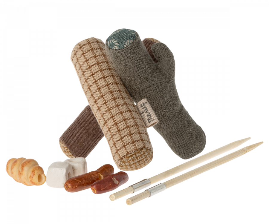 The Maileg Camping Set with Granddad includes plush log-shaped dog toys, small stuffed foods, and two toy roasting sticks—ideal for imaginative camping adventures or playtime with hiking mice and a cozy mouse tent.