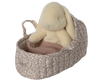 A Maileg Carry Cot, Large - Off White, cradles a plush rabbit toy in cozy floral-patterned fabric, complete with a warm knitted blanket. The carrycot features a convenient small handle and is complemented by the pastel-colored rabbit for an adorable and snug on-the-go companion.