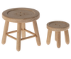 Two small wooden stools with button-patterned tops evoke the charm of farmhouse decor. The larger stool, part of a Maileg Table & Stool Set, Mouse, has a round seat with four legs joined by crossbars for support, while the smaller three-legged stool could easily belong in a mouse family furniture collection. Both feature smooth, unfinished surfaces.