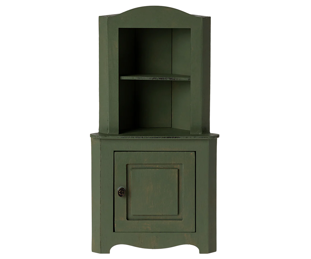 The Maileg Large Corner Cabinet in dark green is a stylish home decoration piece, featuring an upper open shelf section and a lower section with a single door that includes a knob. It showcases a slightly distressed finish for vintage charm, making it perfect for fitting into any corner space.