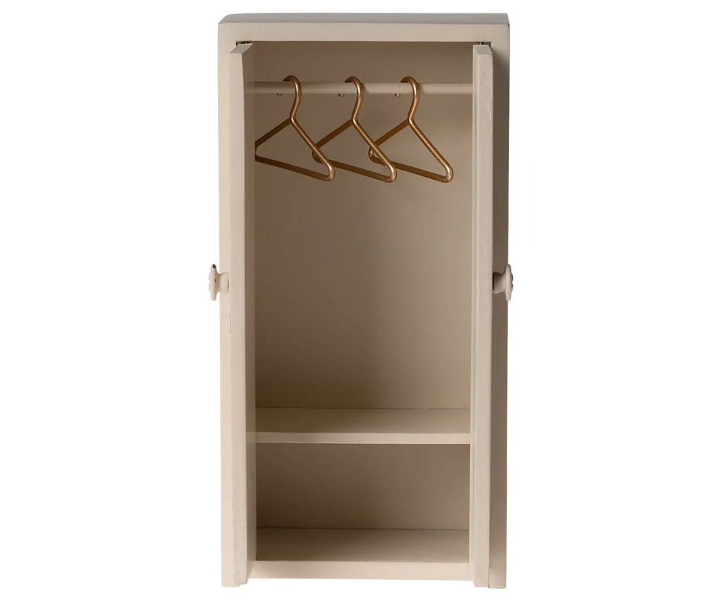 The Maileg Mouse Closet in a cream color is a compact, open wardrobe featuring two shelves, a rail with three golden hangers, and a straightforward, minimalist design.