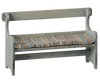 The Maileg Mouse Bench - Off-White features a vintage wooden design with a high back and armrests, adorned with a colorful striped, hand-painted seat cushion. Its comfortable seat and rustic worn finish enhance its antique charm.