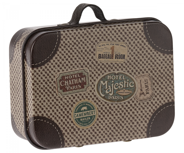 The Maileg Suitcase, Micro is a small rectangular piece with a vintage charm, showcasing a beige and brown checkered pattern. Decorated with an array of travel stickers such as "Hotel Majestic Paris," "Hotel Chatham Paris," and "Baggage Room," it is perfect for storing small items. The suitcase also features a black handle on top for easy carrying.