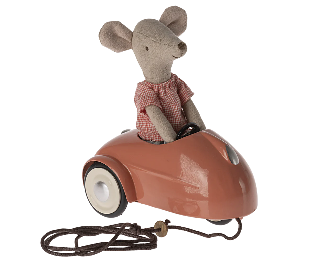 A Maileg Mouse Car - Coral wearing a red and white checkered shirt, seated in a miniature vintage-style metal car, with a pull-cord attached to the front.