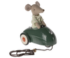 A Maileg Mouse Car - Dark Green sits in a green vintage-style metal car with a pull-string attached in front, against a striped background.