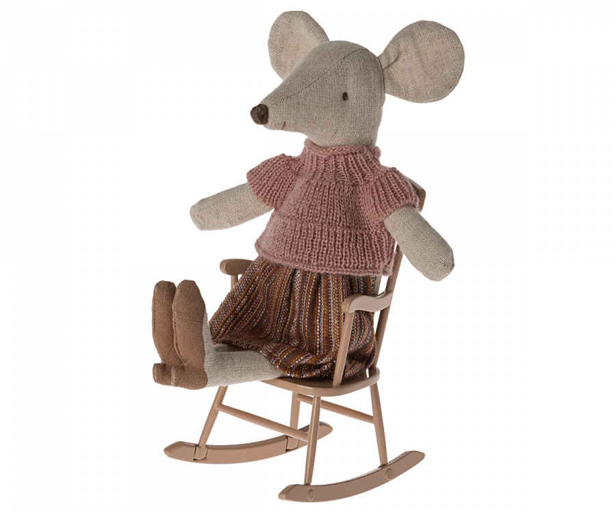 A stuffed toy mouse dressed in a knitted pink top and a striped skirt sits in a Maileg Rocking Chair, Mouse - Dark Powder. The mouse has large beige ears and a pointed snout, with small legs and feet. The scene is whimsical and charming, showcasing delightful mouse accessories.