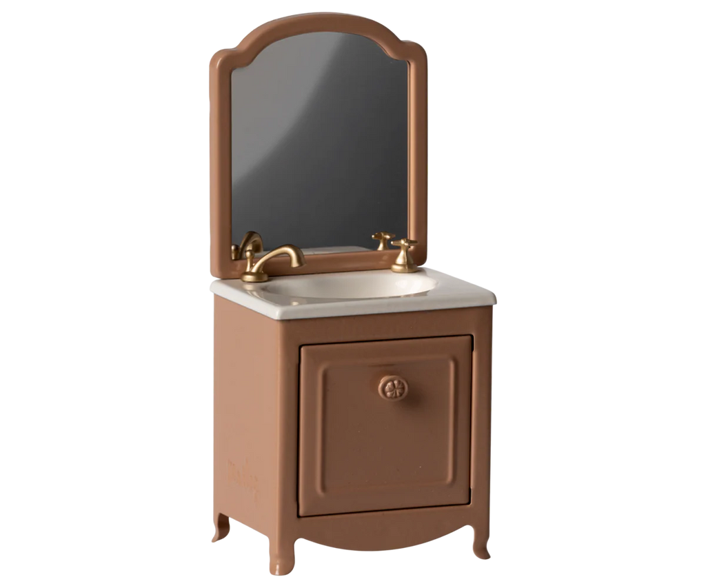 The Maileg Bathroom Set includes a small brown vanity with a white countertop, gold faucet, large rectangular mirror, closed cabinet door under the sink, and four short legs—ideal for furnishing a Maileg mouse bathroom.