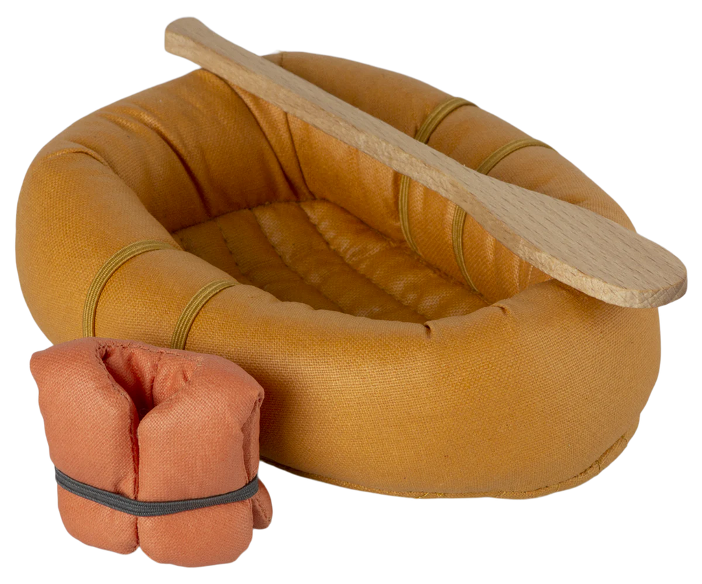 A small, fabric inflatable boat with wooden paddles and an orange life jacket attached is perfect for a pretend water adventure. The Maileg Rubber Boat is orange with a textured surface, and two rectangular wooden paddles rest on top. The bundled orange life jacket, secured by a black strap, sits next to the boat.