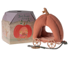 A plush pumpkin carriage toy sits next to its cardboard packaging. The packaging reads "Maileg Pumpkin Carriage" and features an illustration of a fairytale carriage. The plush toy has a pink exterior, polka-dot interior, and golden wheels—truly the perfect carriage for any royal mice family.