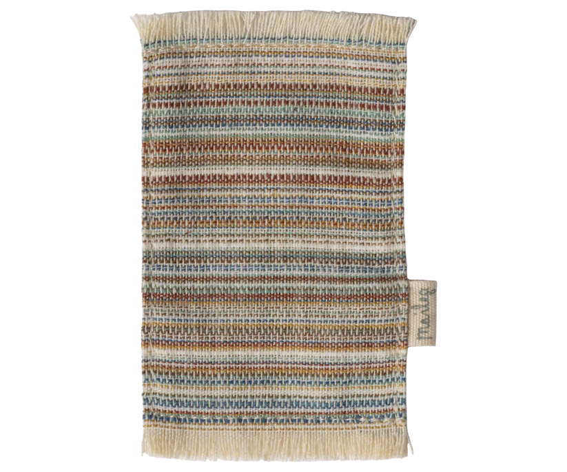 A rectangular woven fabric swatch with fringed edges showcases horizontal stripes in brown, blue, yellow, beige, and white. Perfect for dollhouse decor or enhancing your Maileg Fully Furnished Suitcasa. Includes a right-side fabric tag.