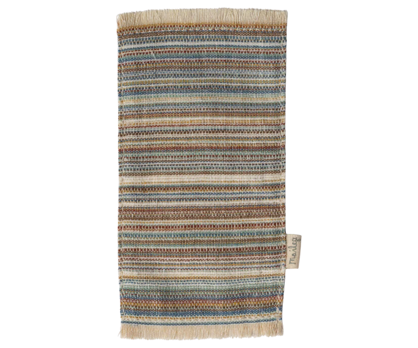 Introducing the Maileg Striped Rug, Medium: a textured, multicolored woven door mat adorned with horizontal stripes in hues of blue, brown, and beige. This charming small striped rug boasts tasseled edges and includes a small label on one side, perfect for adding character to entrances or even enhancing doll houses.