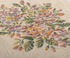 Close-up of the Maileg Flower Rug, Large, featuring a floral cross-stitch pattern on a textured fabric. The embroidery highlights vibrant flowers in shades of purple, pink, orange, and yellow, with green leaves intricately woven into a decorative design. (Ships in approximately one week)