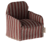 The Maileg Chair, Mouse - Striped is a cozy, fabric-wrapped seat with red and gray vertical stripes, ideal for your Maileg friends. It has boxy armrests, a straight back with a textured look, and a tag on one side, making it perfect to place beside your Gingerbread House décor.