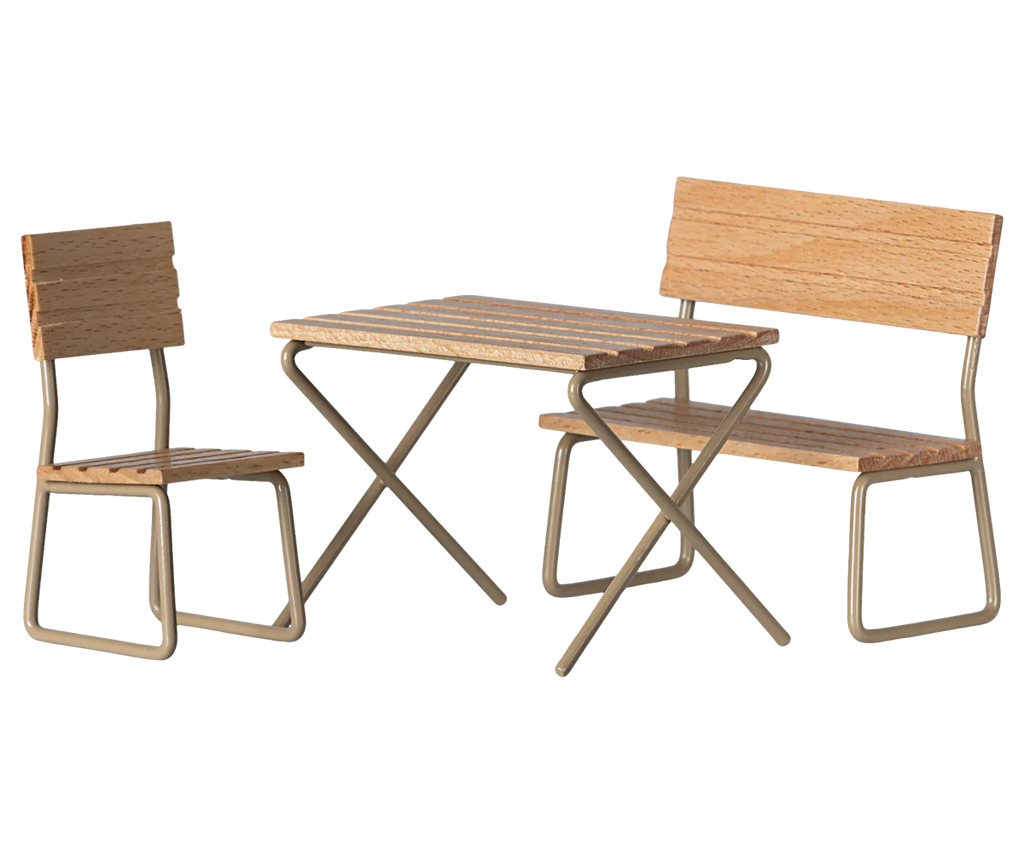 The Maileg Garden Table & Chair Set - Mouse Size is a charming three-piece wooden bistro ensemble featuring a square table, chair, and bench with slats and metal legs, perfect for transforming any outdoor area into a cozy nook. Ships in approximately one week.