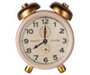 The Maileg Alarm Clock For Dollhouse - Powder, shipping in a week, is a vintage-style pink clock with two brass bells and charming metal accents. Its face shows numbers 1 to 12, small details like repeat and alarm dials, and the hands indicating 10:10.