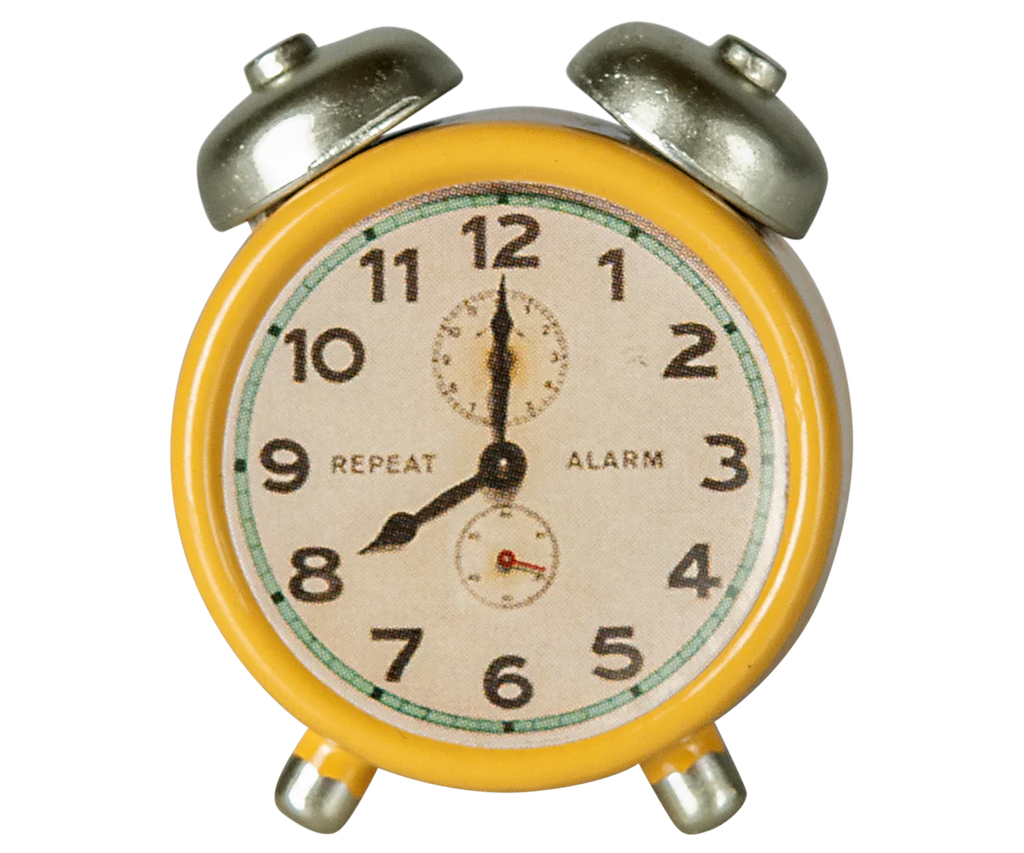 A vintage-style yellow Maileg Alarm Clock for dollhouses features twin bells, a white face with black numerals and hands showing 10:10, "REPEAT" and "ALARM" dials. Suitable for ages 3+. Ships in approx. one week.