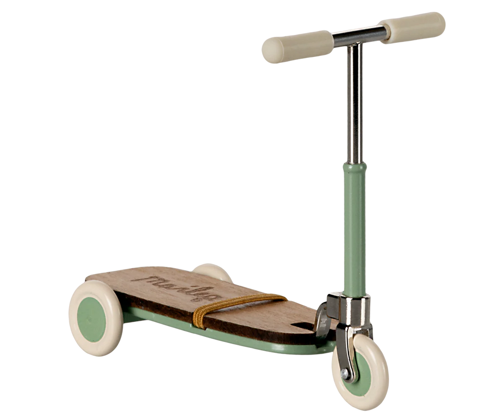 The Maileg Mouse Size Scooter/Kickboard showcases a three-wheeled design with a wooden deck and mint handlebars. Its white wheels enhance the sleek, minimalist look, complemented by elegant wooden details. Ships in approximately one week.