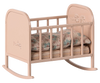 The PRE-ORDER: Maileg My Cradle - Light Rose (ships late January) is a small pink rocking cradle featuring floral engravings on the headboard. It includes a striped mattress and patterned pillow for a cozy look similar to a soft sleeping bag.