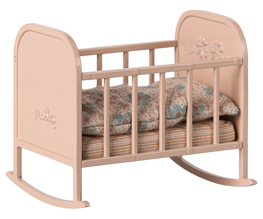 The PRE-ORDER: Maileg My Cradle - Light Rose (ships late January) is a small pink rocking cradle featuring floral engravings on the headboard. It includes a striped mattress and patterned pillow for a cozy look similar to a soft sleeping bag.