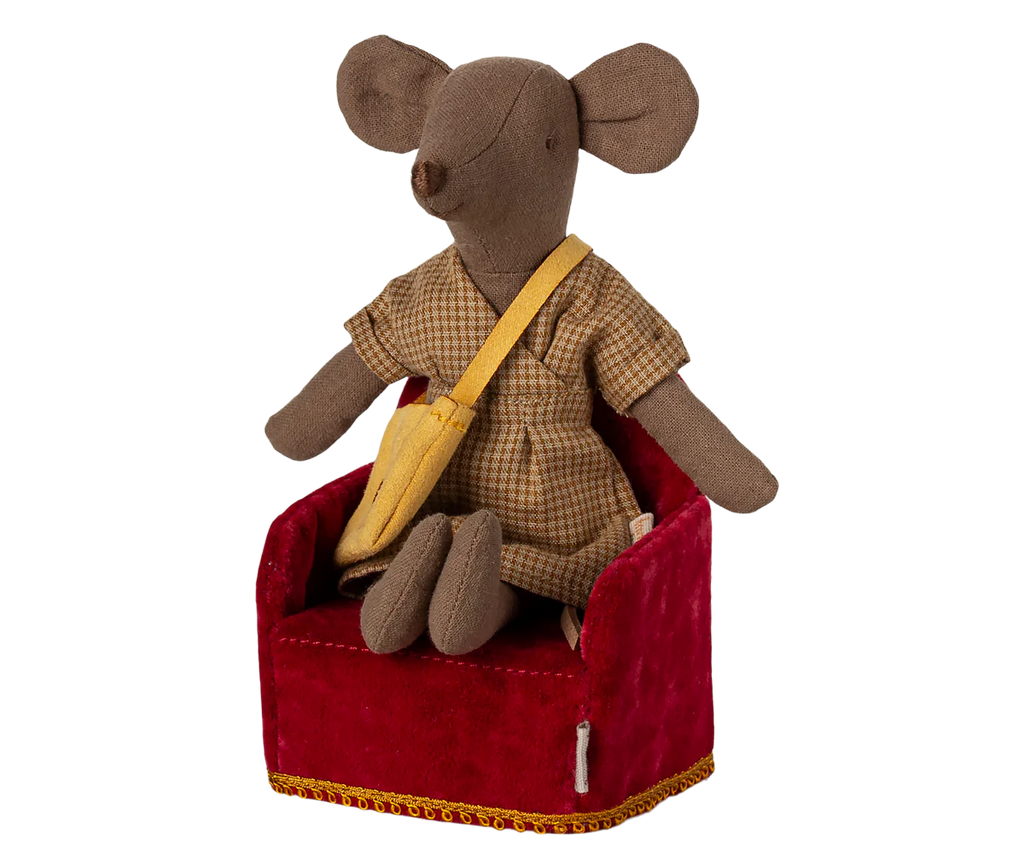 A charming Maileg mouse toy, donned in a plaid outfit with a yellow shoulder bag, sits on the Maileg Soft Chair in Red, perfect for adding whimsy to any Mouse hole Farmhouse setting. Note: Chair is under pre-order and ships in late February.