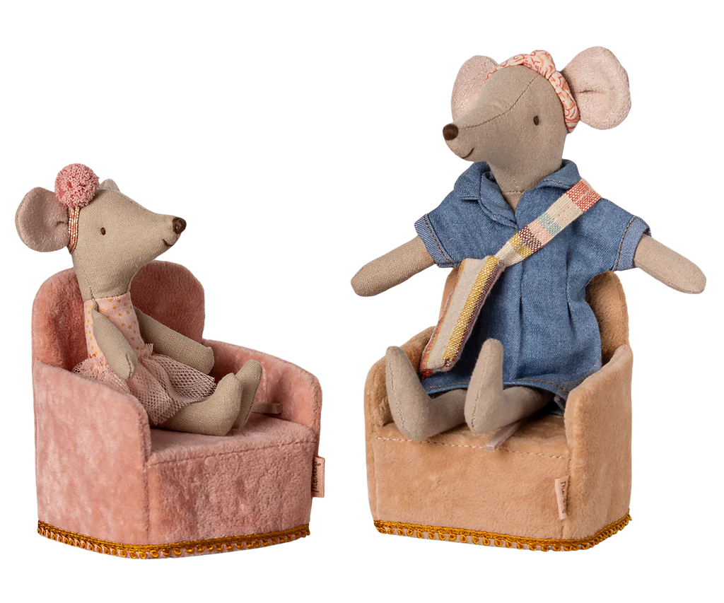 Two Maileg mouse toys sit on soft beige plush chairs adorned with gold-trim accents. The left mouse wears a pink dress and headband, while the right wears blue with a pink and yellow sash. Resembling a cozy farmhouse corner, both chairs are the PRE-ORDER: Maileg Soft Chair - Rose.