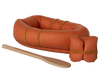 The Maileg Rubber Boat includes a small orange rubber boat with yellow bands, an orange bundle, and a wooden paddle—ideal outdoor accessories for adventurous hiker mice—shown on a white background.