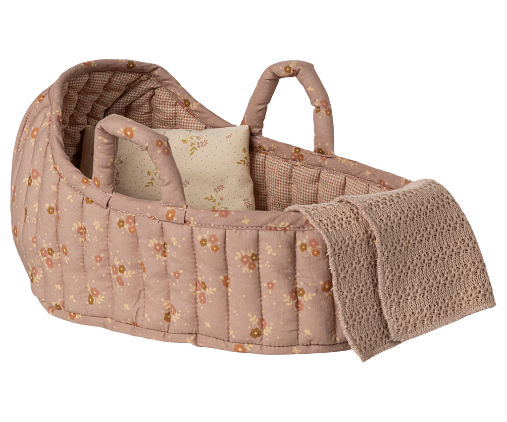 The Maileg Carry Cot, Large - Rose features a pink quilted design with floral patterns, two handles, a star pillow, and a beige knitted blanket—ideal for carrying small plush friends wherever you go.