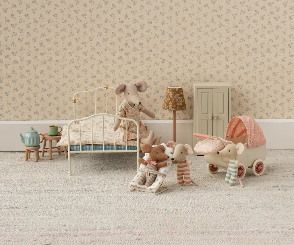 The Maileg My Babysitter - Multi Dots set features charming toy mice and baby mice, a stroller, bed, tiny wardrobe, lamp, tea set, and cradle on a soft rug—all against floral wallpaper for a cozy miniature bedroom scene.