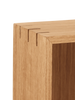Close-up of a Ferm Living Bon Shelf - Oiled Oak corner showing detailed wood grain and a precise dovetail joint in oiled oak, isolated on a black background.